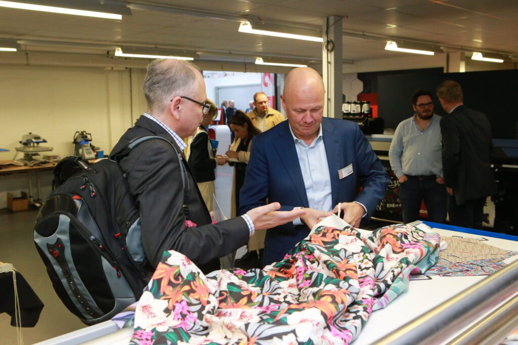 Marc Verbeem knipt een stuk geprint textiel af voor een geïnteresseerde bezoeker.