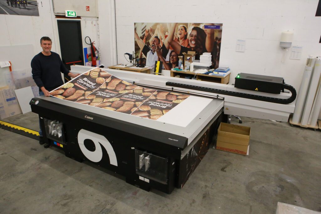 Frank Duijn bij de Arizona 1360 GTF vlakbedprinter van Canon, uitgerust met witte inkt, voor het printen van plaatmaterialen.