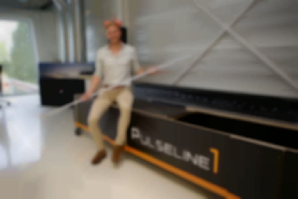 Myhron Werts, gezeten op een kist waarin onderdelen voor de dynamische lichtlijn worden vervoerd, toont een segment van Pulseline1.